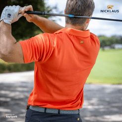 Man swinging a golf club wearing a blaze orange polo.