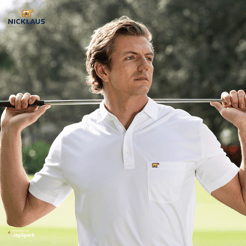 Man wearing a white polo with a golf club resting on his shoulders.